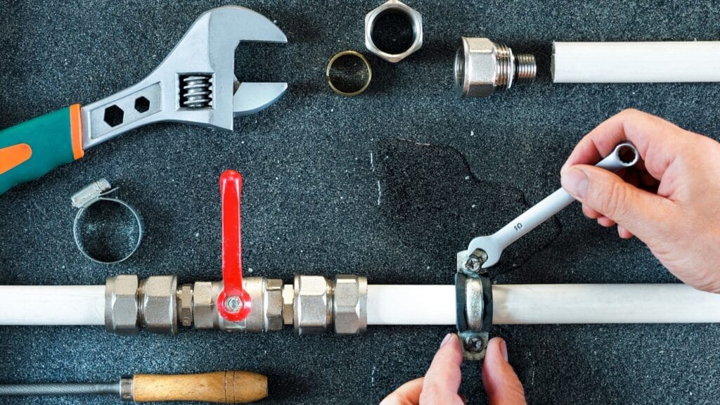 Plumber repairing a pipe valve with an adjustable wrench in Palm Beach Gardens