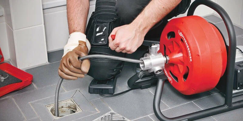 Plumber using a drain-cleaning machine in Palm Beach Gardens