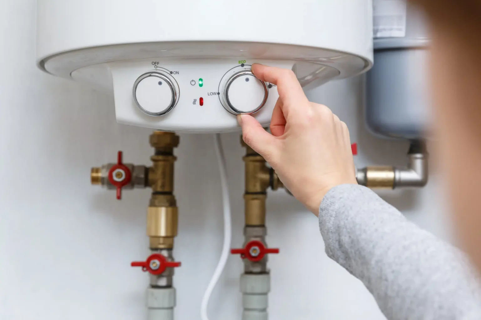 Homeowner adjusting the temperature controls on a water heater in Palm Beach Gardens